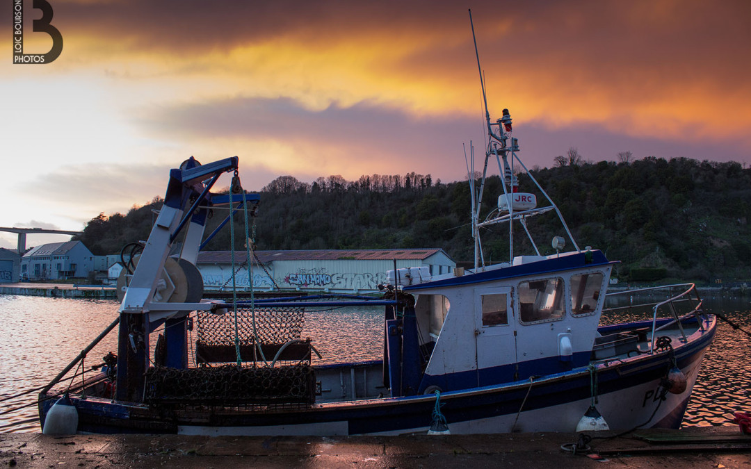Bateau de pêche dans le port avec couché de soleil